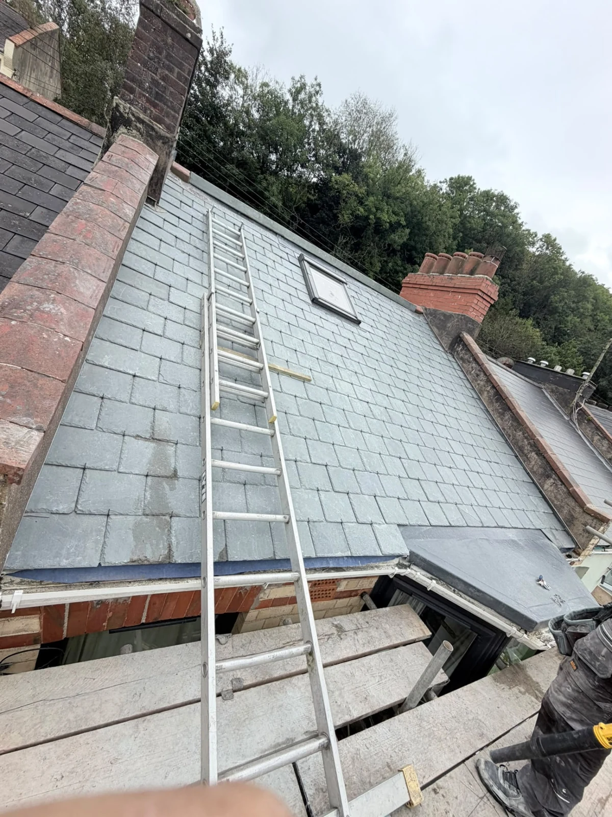 Slate pitched roof and roof window viewed from scaffolding