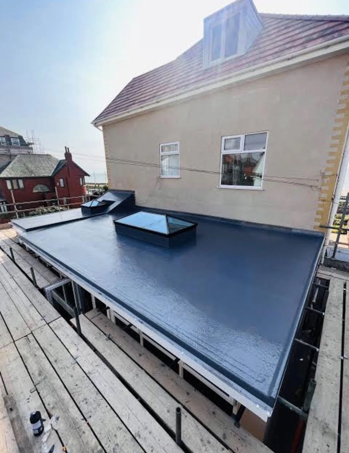 Flat roof covering with an upstand beside a rendered house