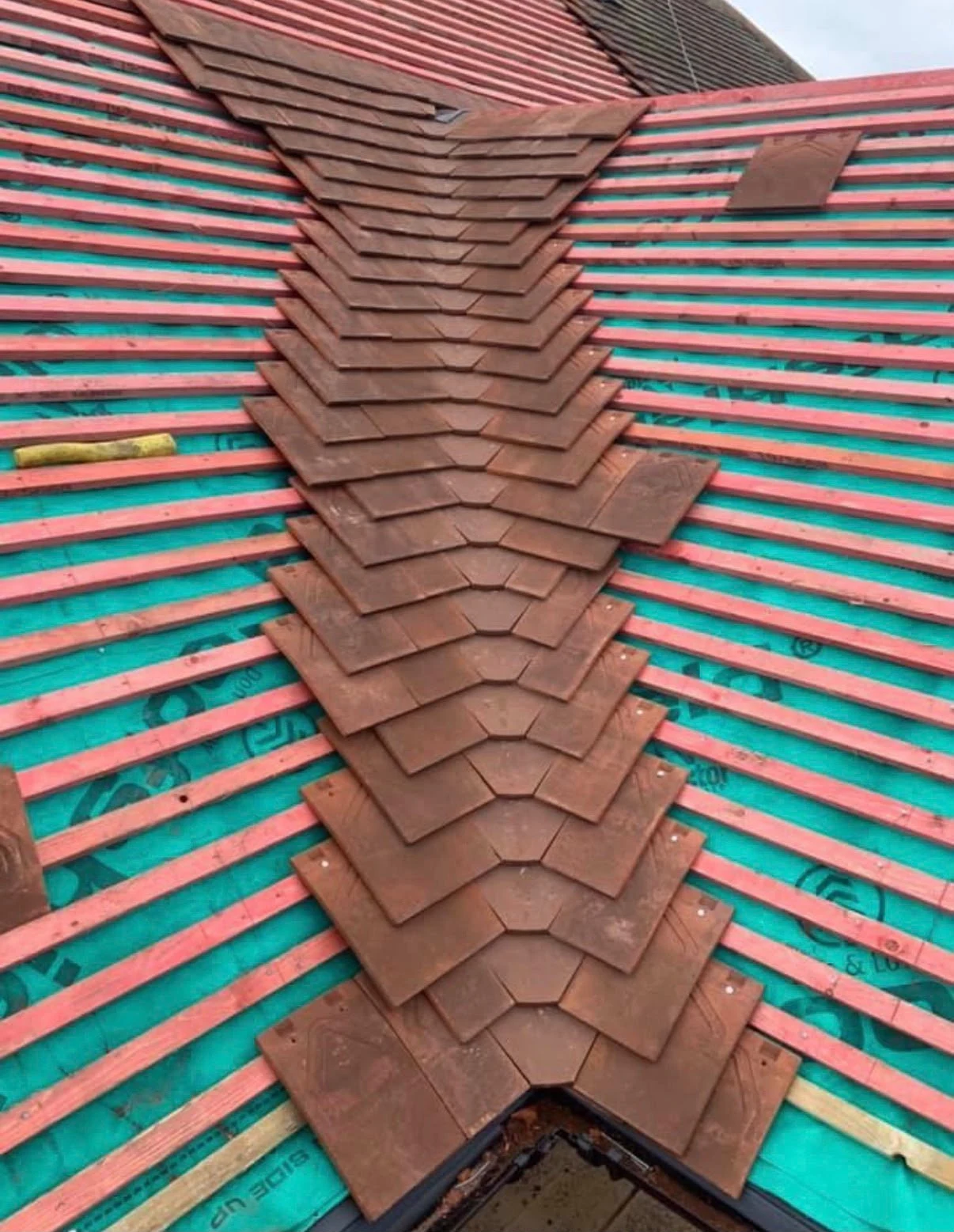 Pitched roof hip with tiles being fitted over timber battens
