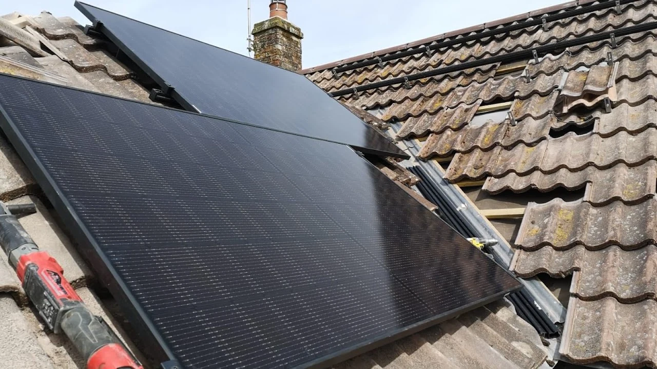 Dark flat roof covering between pitched tiled roof slopes