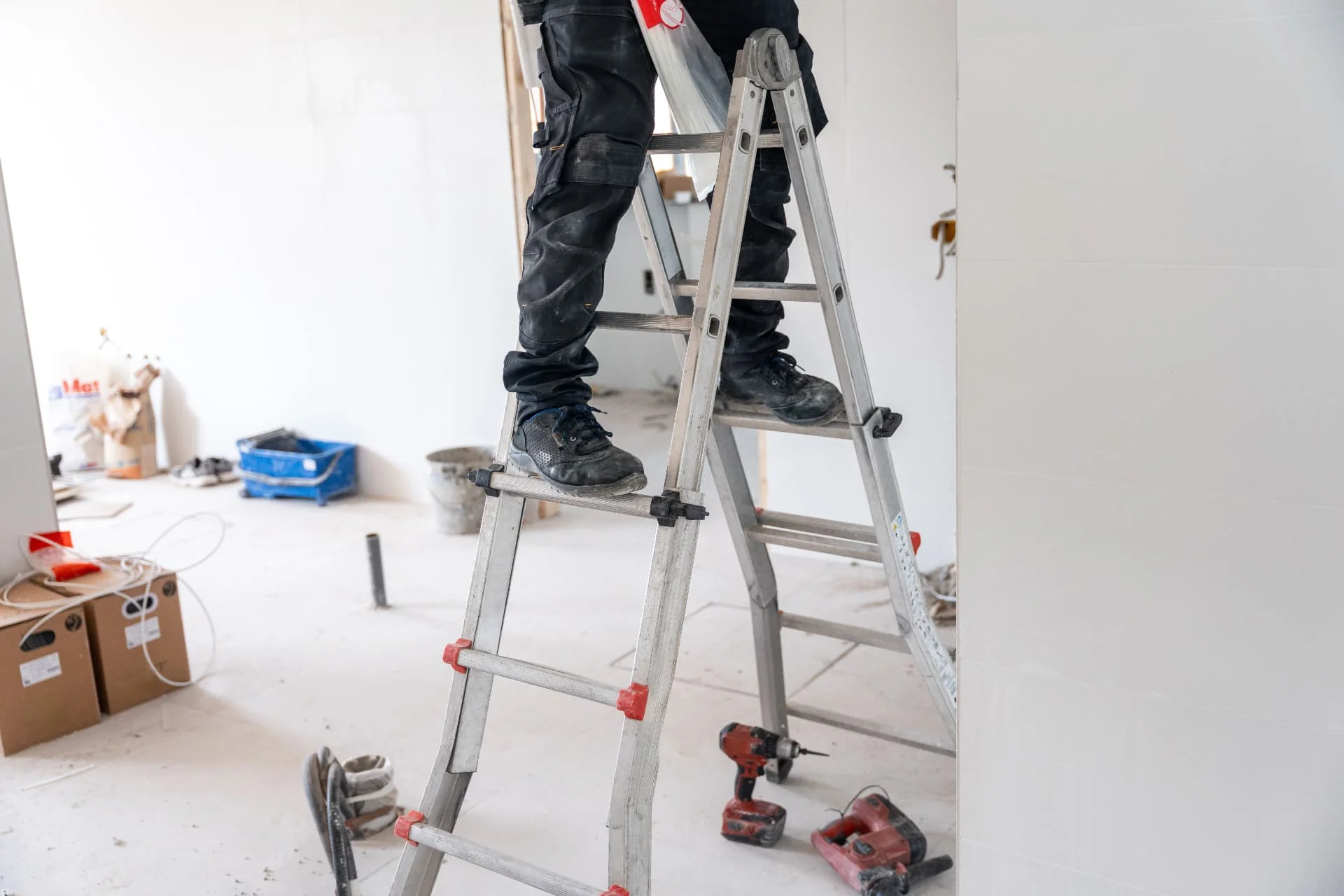 Worker on a stepladder with tools during interior building work
